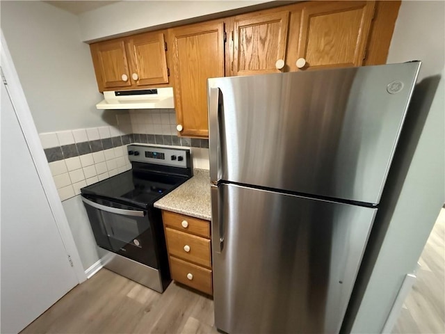 kitchen with tasteful backsplash, light hardwood / wood-style flooring, and appliances with stainless steel finishes