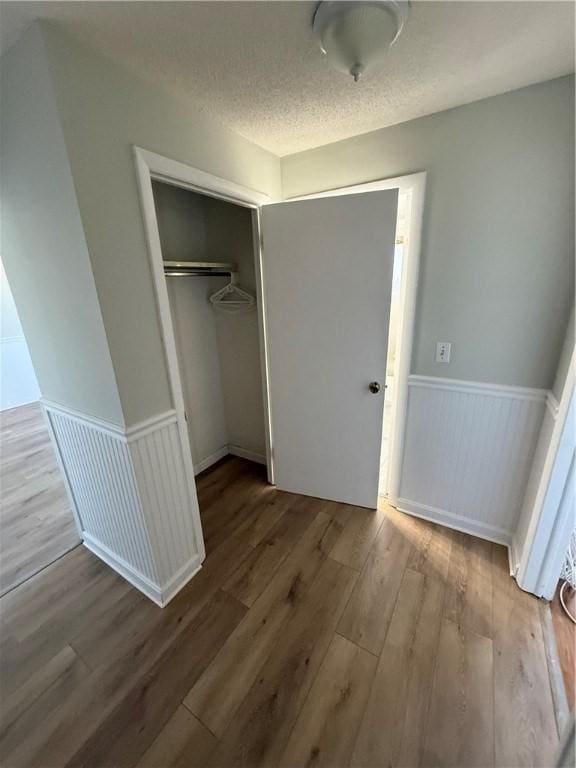 unfurnished bedroom with light hardwood / wood-style flooring, a textured ceiling, and a closet