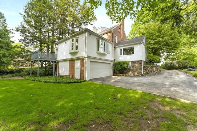 9 Dennison Rd, Worcester, MA 01609 - view of front of home with brick siding, an attached garage, asphalt driveway, a front lawn, and a wooden deck