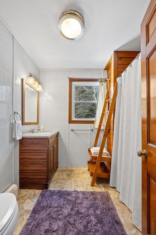 full bath featuring toilet, vanity, and tile walls