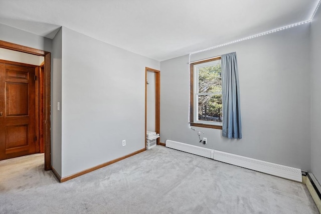 unfurnished room with a baseboard heating unit, carpet floors, and baseboards