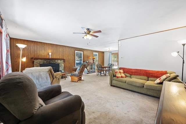 carpeted living area featuring a ceiling fan, a fireplace, and wood walls