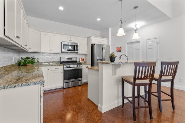 22 Grey Hawk Dr Unit 22, Mashpee, MA 02649 - kitchen with white cabinets, a breakfast bar, backsplash, and appliances with stainless steel finishes