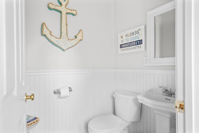 half bathroom with toilet and wainscoting