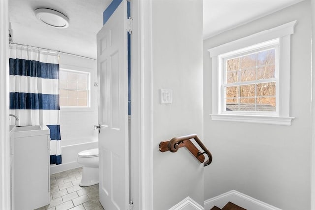 bathroom with shower / bath combination with curtain, toilet, baseboards, and a sink