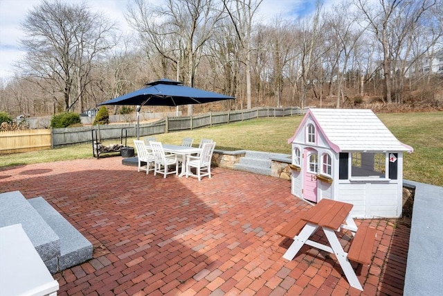 view of patio with an outbuilding, outdoor dining area, and a fenced backyard