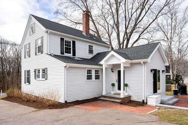 view of front of house featuring a chimney and a shingled roof