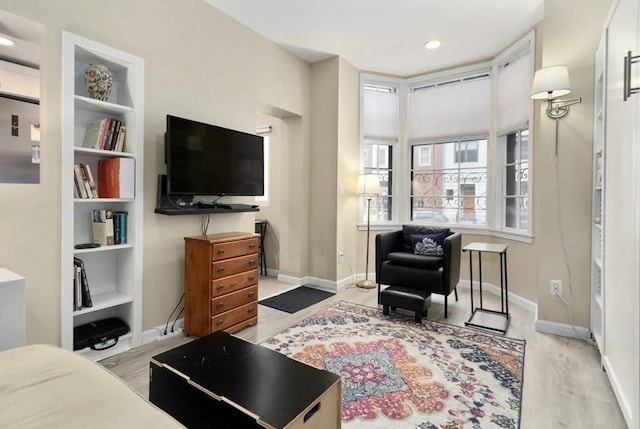 living room with built in shelves and light hardwood / wood-style floors