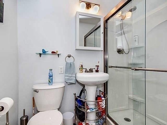 bathroom featuring a shower with door and toilet