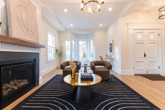 living area with a chandelier, light wood-type flooring, and crown molding