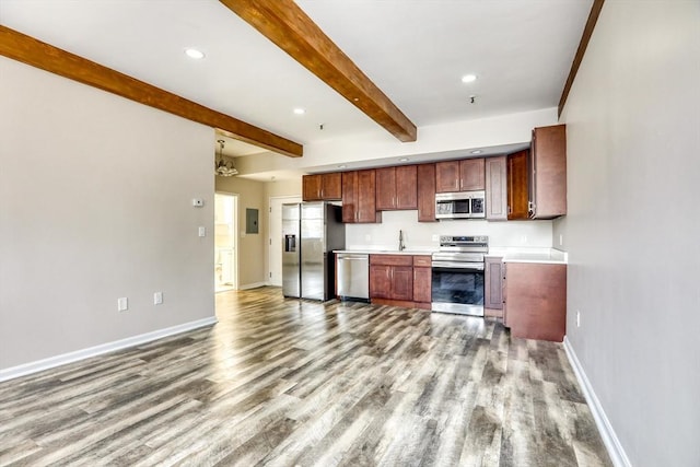 kitchen featuring beam ceiling, sink, light hardwood / wood-style floors, and appliances with stainless steel finishes