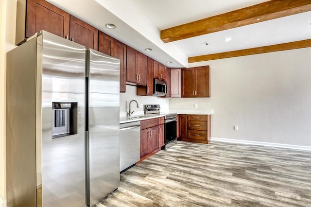 kitchen featuring beam ceiling, light hardwood / wood-style flooring, stainless steel appliances, and sink