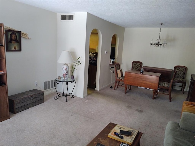 carpeted living area with arched walkways, a textured ceiling, visible vents, and a notable chandelier