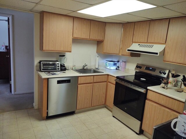 kitchen with range hood, light countertops, appliances with stainless steel finishes, a sink, and a drop ceiling