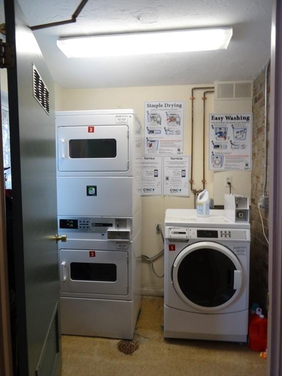 shared laundry area with stacked washer and dryer and visible vents