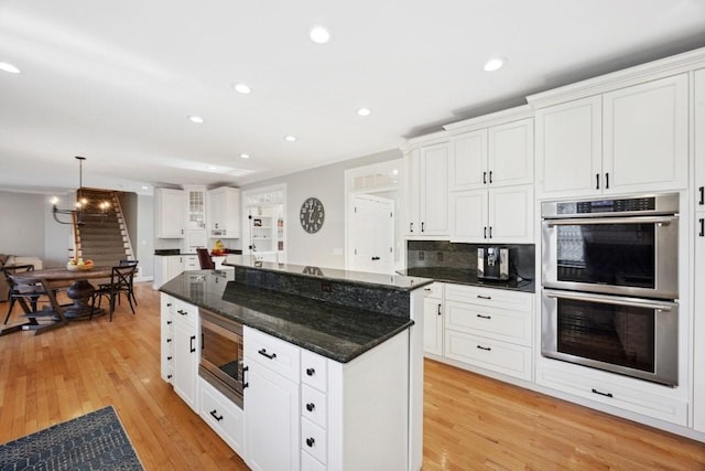 kitchen with a center island, white cabinetry, recessed lighting, stainless steel appliances, and light wood-style floors