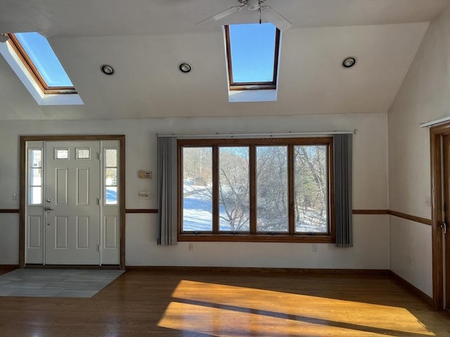 foyer featuring lofted ceiling with skylight, baseboards, and wood finished floors