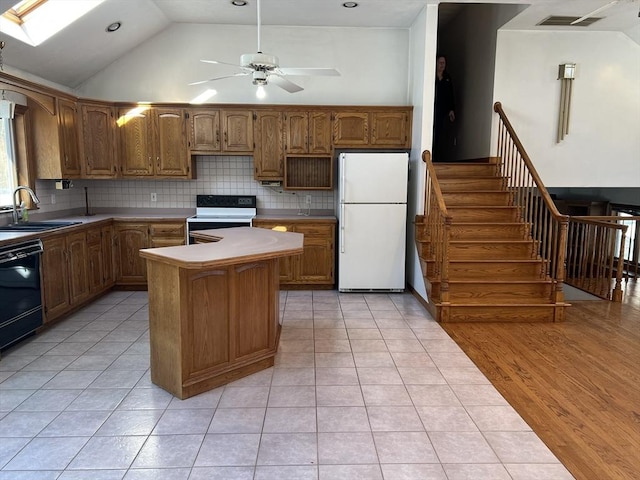 kitchen featuring a skylight, tasteful backsplash, a sink, a kitchen island, and white appliances