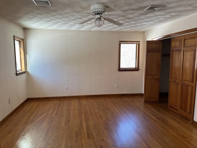 unfurnished bedroom featuring baseboards, visible vents, wood finished floors, a textured ceiling, and a closet