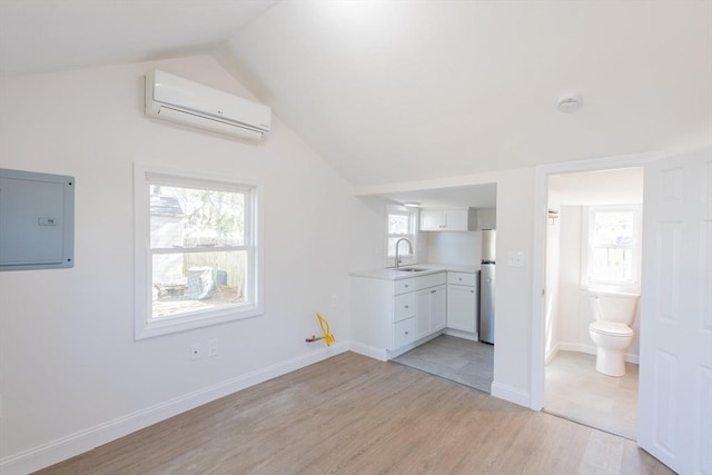 9 Bells Neck Rd Unit 4, Harwich, MA 02671 - unfurnished bedroom featuring an AC wall unit, light wood finished floors, a sink, electric panel, and vaulted ceiling