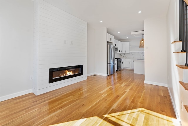 unfurnished living room with a large fireplace and light hardwood / wood-style floors