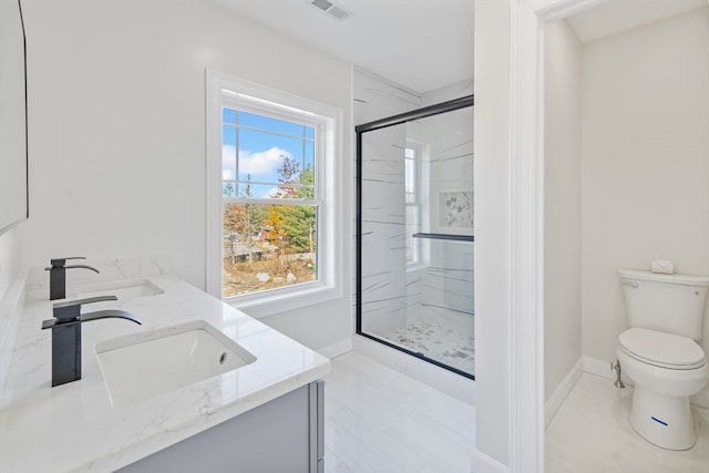 bathroom with a wealth of natural light, a shower with shower door, vanity, and toilet