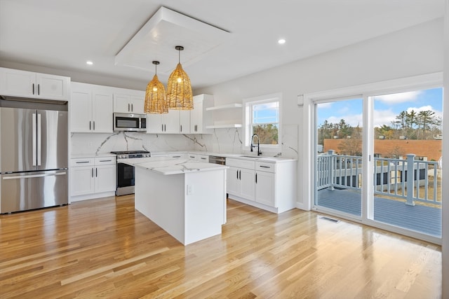 kitchen with white cabinets, hanging light fixtures, sink, and stainless steel appliances