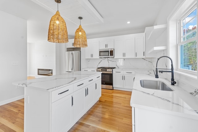 kitchen featuring stainless steel appliances, white cabinets, hanging light fixtures, sink, and light hardwood / wood-style flooring