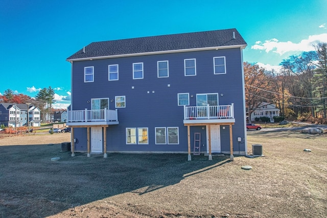 rear view of property featuring a lawn, a balcony, and cooling unit