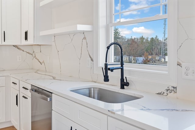 kitchen featuring sink, light stone counters, white cabinets, dishwasher, and decorative backsplash