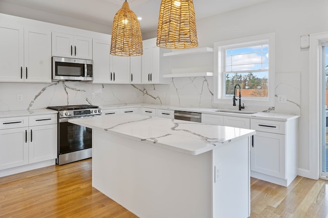 kitchen featuring sink, appliances with stainless steel finishes, decorative light fixtures, a kitchen island, and white cabinets