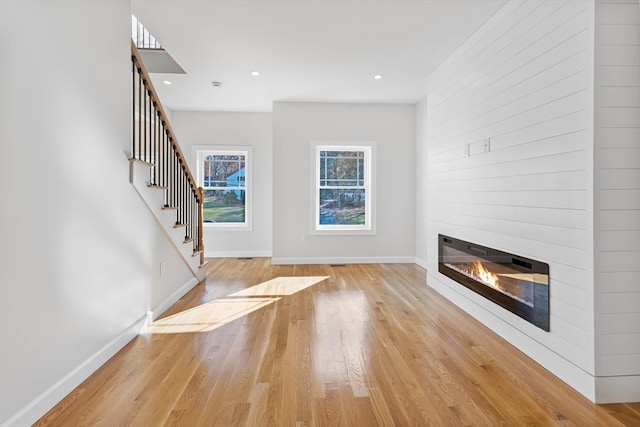 unfurnished living room with light wood-type flooring and a large fireplace