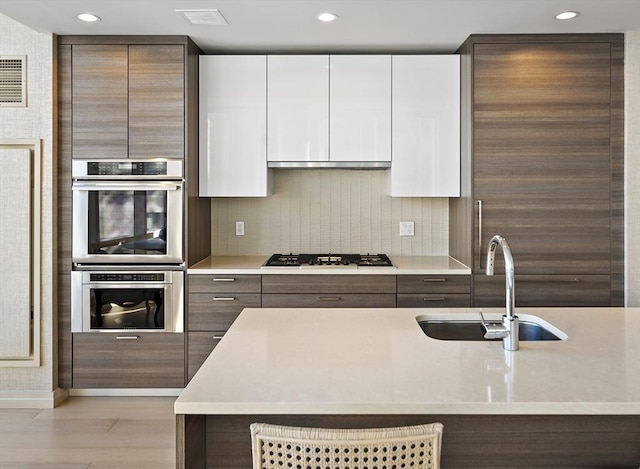 kitchen featuring a sink, light countertops, gas stovetop, and stainless steel double oven