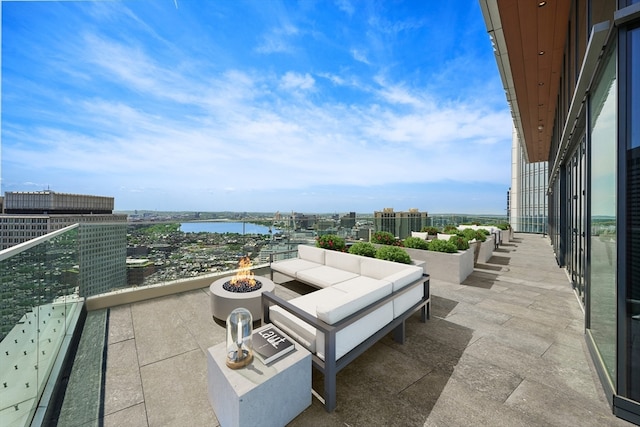 view of patio / terrace featuring a water view, an outdoor living space with a fire pit, and a balcony