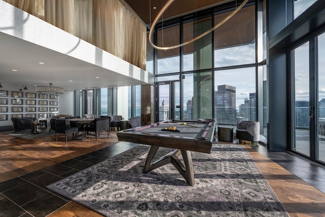 recreation room featuring pool table, a wealth of natural light, dark hardwood / wood-style floors, and a high ceiling