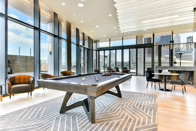 playroom featuring a towering ceiling, wood-type flooring, billiards, and floor to ceiling windows