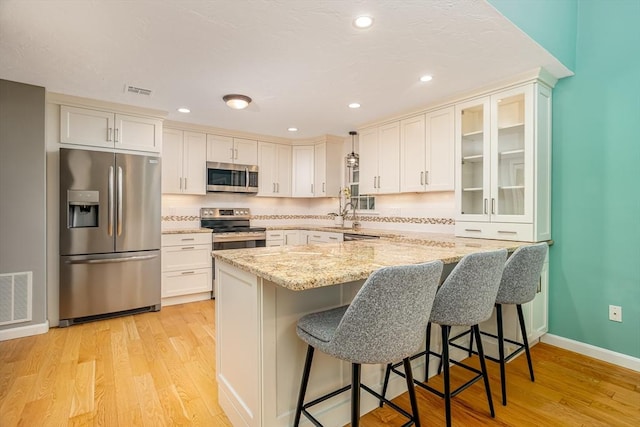 706 Ridgefield Cir Unit A, Clinton, MA 01510 - kitchen featuring appliances with stainless steel finishes, light stone countertops, light wood-style floors, a kitchen breakfast bar, and recessed lighting