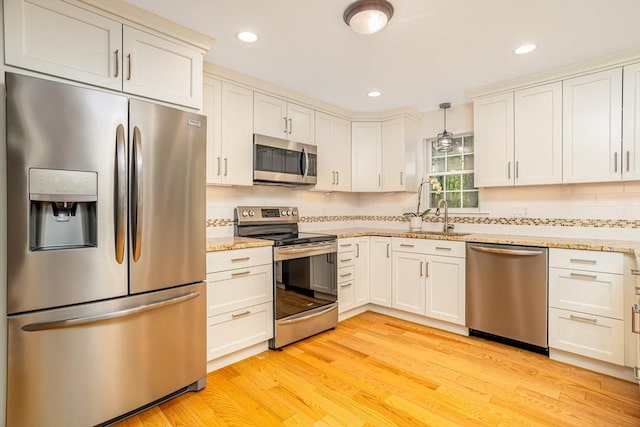 706 Ridgefield Cir Unit A, Clinton, MA 01510 - kitchen featuring appliances with stainless steel finishes, light wood-style flooring, decorative backsplash, light stone counters, and recessed lighting