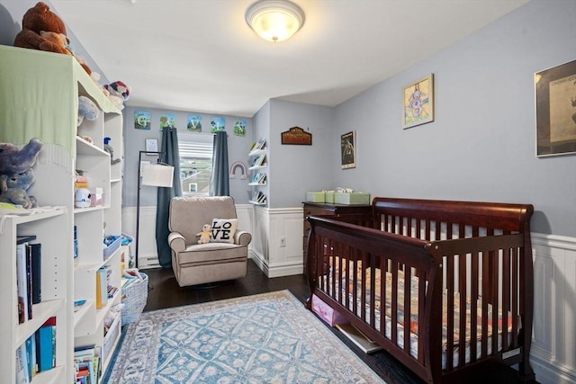 143 Morton St, Winthrop, MA 02152 - bedroom featuring a wainscoted wall, wood finished floors, a crib, and a decorative wall
