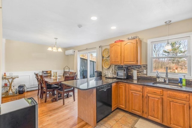 kitchen featuring a wall mounted air conditioner, plenty of natural light, a sink, and dishwasher