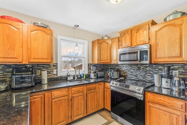 kitchen featuring backsplash, pendant lighting, a sink, dark stone countertops, and stainless steel appliances