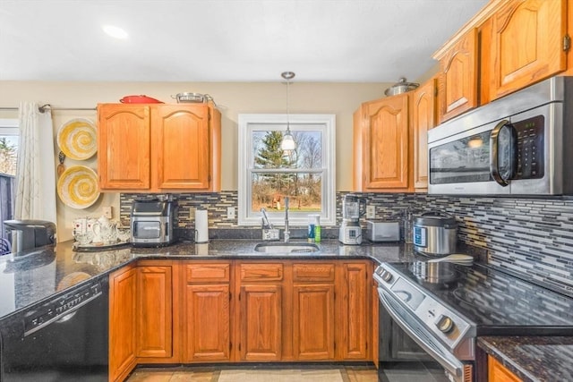 kitchen featuring dark stone counters, stainless steel appliances, a sink, and backsplash