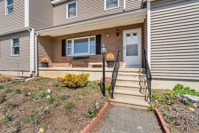 view of exterior entry with covered porch and brick siding
