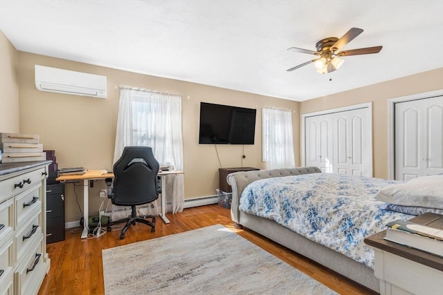 bedroom featuring multiple closets, a wall mounted AC, multiple windows, and wood finished floors