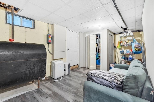 living area featuring a drop ceiling, heating fuel, and wood finished floors