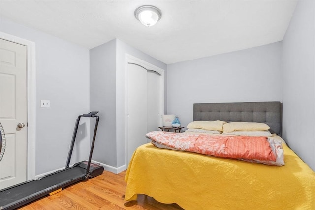 bedroom with baseboards, wood finished floors, and a closet