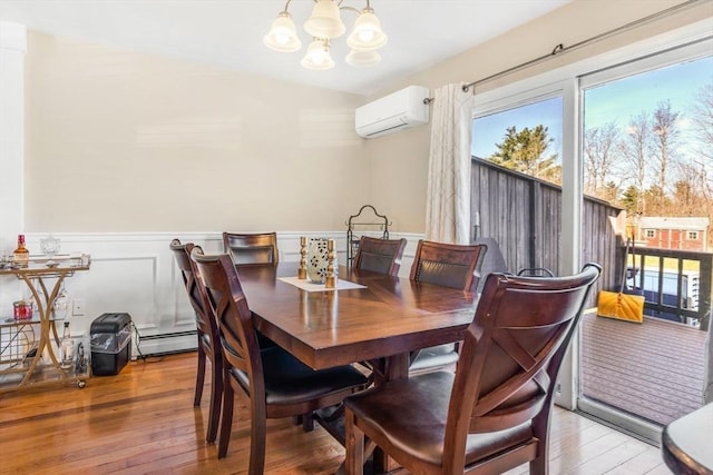 dining room with a wall mounted AC, hardwood / wood-style flooring, a wainscoted wall, a baseboard radiator, and an inviting chandelier
