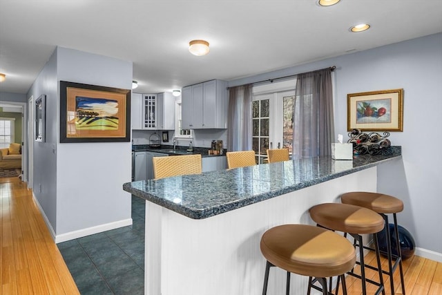 kitchen with plenty of natural light, a kitchen bar, kitchen peninsula, and white cabinets