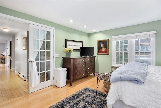 bedroom featuring baseboard heating and light hardwood / wood-style flooring