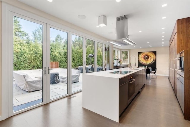 kitchen featuring sink, french doors, island exhaust hood, black electric cooktop, and a center island with sink